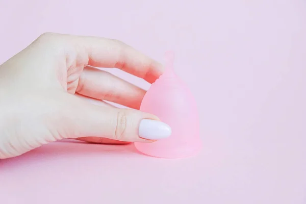 Wanita muda tangan memegang cangkir menstruasi. Cangkir menstruasi dengan latar belakang merah muda. Produk higenitas feminin alternatif selama periode tersebut. Konsep kesehatan perempuan — Stok Foto
