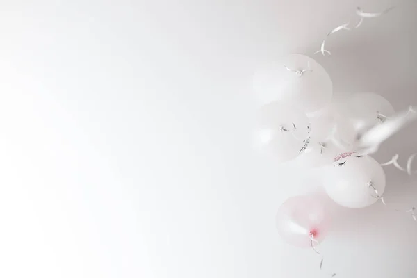 White balloons with streamers isolated on the ceiling in room prepared for birthday party. Copyspace for text