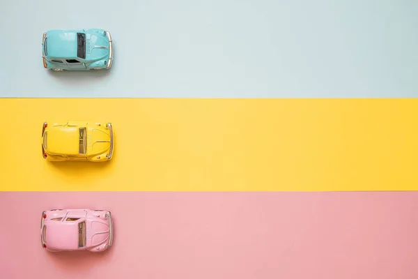 Kleine farbige Spielzeugautos am Start auf einem gelben, rosa und blauen Bac — Stockfoto