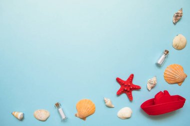 Kopya alanı ile mavi deniz arka plan üzerinde deniz kabukları, kırmızı denizyıldızı ve oyuncak tekne ile Çerçeve. Plaj tatili konsepti, gemi seyahati. Yaz düz yatıyordu.