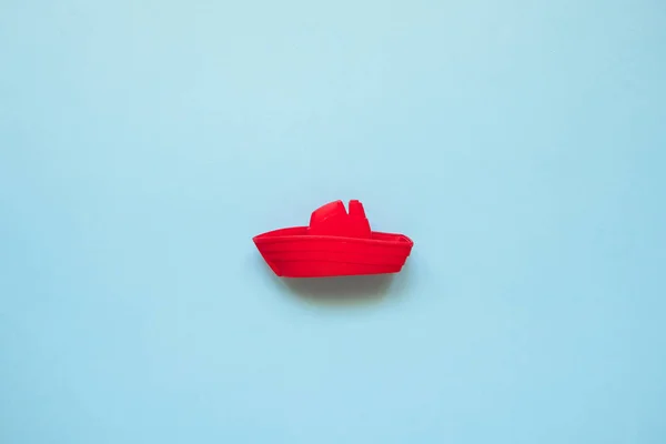 Rotes Spielzeugboot auf blauem Meeresgrund mit Kopierraum. Strandurlaub, Kreuzfahrt. Sommer minimal flach gelegt — Stockfoto