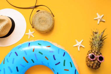 Renkli yaz düz mavi şişme daire donut, güneş gözlüğü komik ananas, hasır şapka, bambu çanta ve sarı arka plan üzerinde denizyıldızı denizyıldızı, üst görünümü ile yatıyordu. Tatil konsepti