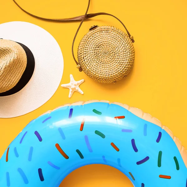Colorful summer flat lay with blue inflatable circle donut, straw hat, bamboo bag and starfish starfish over yellow background, top view. Holiday concept — Stock Photo, Image