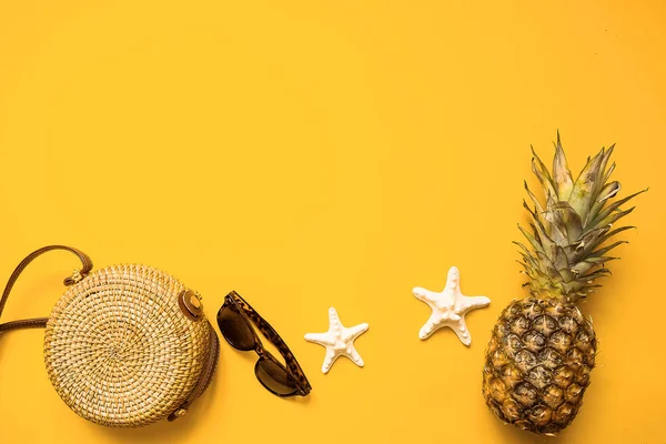 Colorful summer female fashion outfit flat lay. Bamboo bag, sunglasses, pineapple and starfish over yellow background, top view. Summer fashion, holiday concept — Stock Photo, Image
