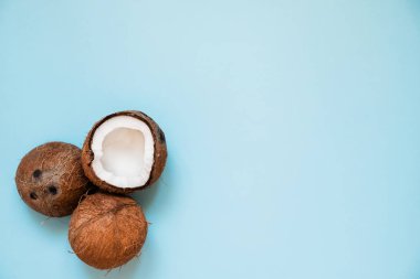 Düz mavi arka plan üzerinde olgun hindistan cevizi ile yatıyordu. Üst Görünüm. Kopya Alanı. Pop art tasarımı, yaratıcı yaz konsepti. Afiş. Minimal düz yatıyordu tarzıhindistan cevizi yarısı.