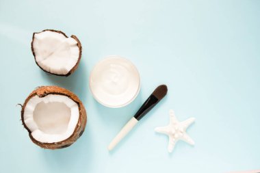 Mavi arka plan üzerinde taze hindistan cevizi yağı ve olgun hindistan cevizi ile açılan cam kavanoz. Organik sağlıklı gıda kavramı. Güzellik ve Spa konsepti