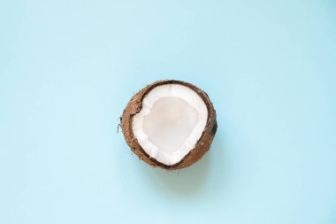 Yaratıcı düzen mavi arka plan üzerinde yarım olgun hindistan cevizi yapılmış. Düz minimal tarzda yatıyordu