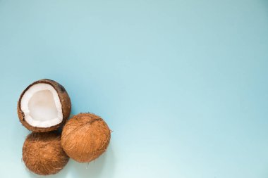 Düz mavi arka plan üzerinde olgun hindistan cevizi ile yatıyordu. Üst Görünüm. Kopya Alanı. Pop art tasarımı, yaratıcı yaz konsepti. Afiş. Minimal düz yatıyordu tarzıhindistan cevizi yarısı.