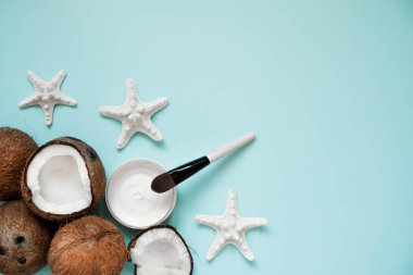 Mavi arka plan üzerinde taze hindistan cevizi yağı ve olgun hindistan cevizi ile açılan cam kavanoz. Ev yapımı hindistan cevizi ürünleri