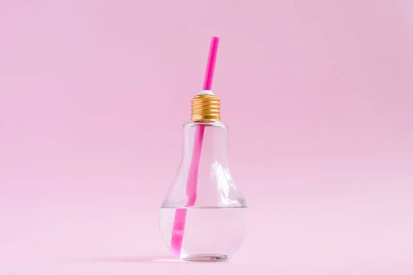 Concept idée créative et innovation avec ampoule. Eau en forme d'ampoule verre sur fond rose — Photo