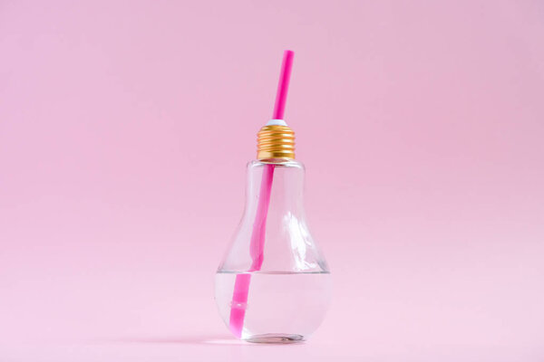 Концепция творческой идеи и инноваций с лампочкой. Вода в форме лампы стекло на розовом фоне
