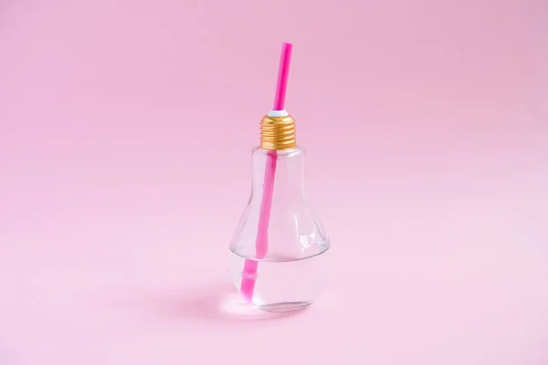 Konzept kreative Idee und Innovation mit Glühbirne. Wasser in lampenförmigem Glas auf rosa Hintergrund — Stockfoto
