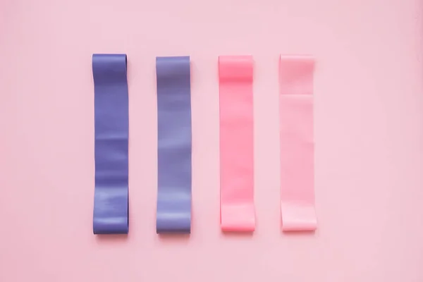 Colorful fitness gums on pink background. Elastic expanders