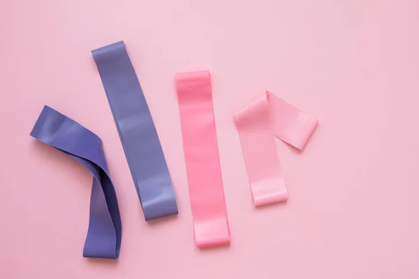 Bunte Fitnessgummis auf rosa Hintergrund. elastische Expander — Stockfoto