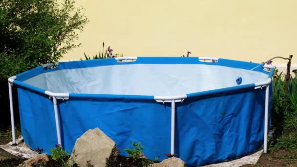 Water dat uit de slang in het zwembad stroomt. Het vullen van een klein zwembad met schoon water. — Stockvideo