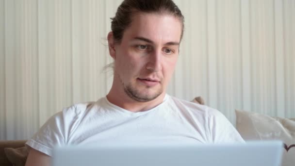 Jeune homme freelance étudiant à l'aide d'un ordinateur portable étudier le travail en ligne de la maison dans Internet, souriant focalisé millénariste gars dactylographier sur le web de surf informatique en regardant l'écran profiter d'un emploi lointain — Video