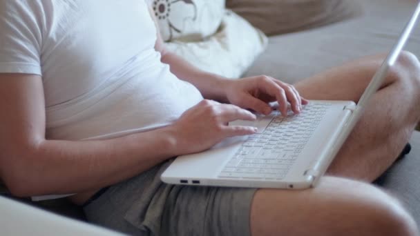 Mladý muž na volné noze student pomocí notebooku studuje on-line pracuje z domova v internetu, usmívá se soustředěný tisíciletý chlap psaní na počítači surfování web při pohledu na obrazovce těší vzdálenou práci — Stock video