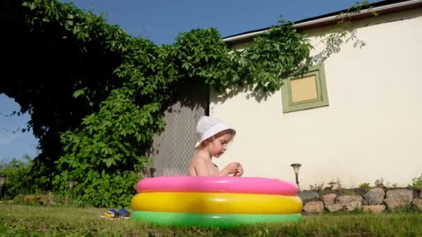 Criança nada em uma piscina inflável. Menina feliz que joga na piscina exterior colorida no dia quente do verão . — Vídeo de Stock