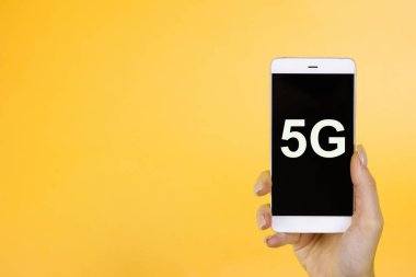 Yaratıcı arka plan, 5G sembollü bir telefonu tutmak. 5G ağı konsepti, yüksek hızlı mobil internet, yeni nesil ağlar