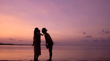 Günbatımında tropikal sahilde dostça aile kucaklaşmaları ve öpücükler. Mutlu aile kavramı. 