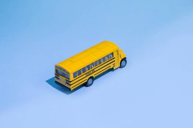 Okul konseptine geri dönelim. Geleneksel sarı okul otobüsü mavi arka planda. Okula nakil ol. Sarı oyuncak model okul otobüsü.