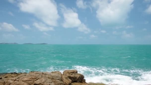 Güçlü dalgalar ve deniz köpüğüyle kayalık bir sahilde kırılma sesleri. Mavi gök mavisi deniz suyu, deniz kıyısı, taş kıyısı. — Stok video