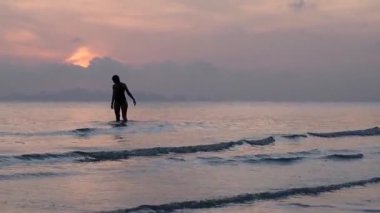 Mutlu Kaygısız Kadın Sahilde Güzel Günbatımının tadını çıkarıyor. Gün batımında suya girip ufku terk eden bir kızın silueti..