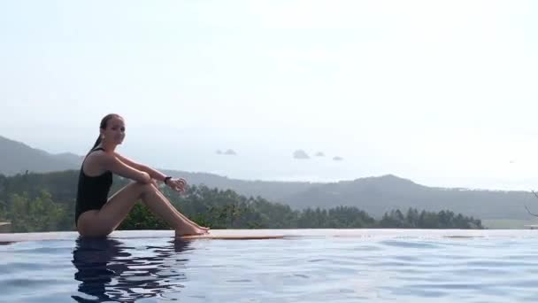 Mulher relaxante na piscina infinita olhando para a vista — Vídeo de Stock