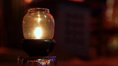 Yağ fenerleriyle dolu bir adada gün batımı romantik sahneyi aydınlatıyor. Arka planda bulanık bokeh. Plajdaki dinlenme kafeteryasında.