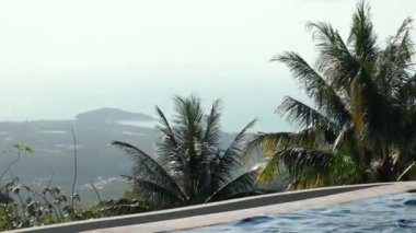 Havuzu ve ada manzaralı bir teras. Dağların, palmiyelerin ve okyanus koyunun güzel manzarası