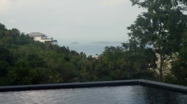 Havuzu ve ada manzaralı bir teras. Dağların, palmiyelerin ve okyanus koyunun güzel manzarası