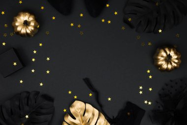 Siyah arka planda cadılar bayramı partisi kadın aksesuarları: peçeli şapka, jartiyer kemeri, hediyeler. Siyah ve altın balkabakları, düz yatış, üst görünüm, kopyalama alanı.