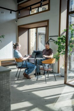 Two men engaged in conversation at a stylish cafe, capturing a relaxed social atmosphere