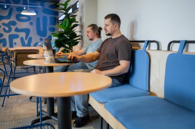 A modern workspace with professionals collaborating on laptops, showcasing productivity and teamwork
