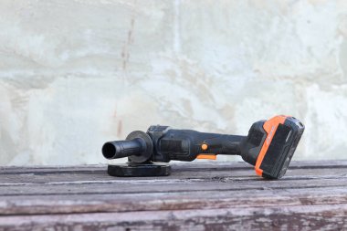 Kablosuz öğütücü yakın planda, ahşap bir yüzeye uzanıyor. Kulübede ya da inşaatta tamirat. Çalışan alet. Kablosuz kablosuz öğütücü. Elektrikli aletler. DIY tamir konsepti, inşaat ekipmanları