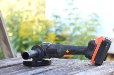 Kablosuz öğütücü yakın planda, ahşap bir yüzeye uzanıyor. Kulübede ya da inşaatta tamirat. Çalışan alet. Kablosuz kablosuz öğütücü. Elektrikli aletler. DIY tamir konsepti, inşaat ekipmanları