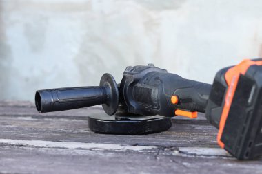 Kablosuz öğütücü yakın planda, ahşap bir yüzeye uzanıyor. Kulübede ya da inşaatta tamirat. Çalışan alet. Kablosuz kablosuz öğütücü. Elektrikli aletler. DIY tamir konsepti, inşaat ekipmanları