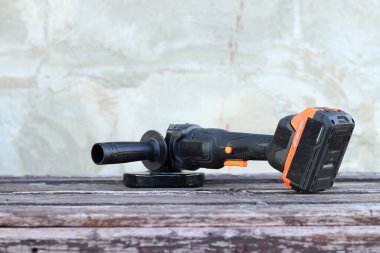 Kablosuz öğütücü yakın planda, ahşap bir yüzeye uzanıyor. Kulübede ya da inşaatta tamirat. Çalışan alet. Kablosuz kablosuz öğütücü. Elektrikli aletler. DIY tamir konsepti, inşaat ekipmanları