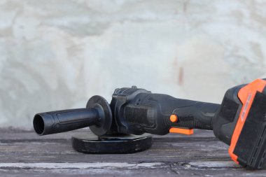 Kablosuz öğütücü yakın planda, ahşap bir yüzeye uzanıyor. Kulübede ya da inşaatta tamirat. Çalışan alet. Kablosuz kablosuz öğütücü. Elektrikli aletler. DIY tamir konsepti, inşaat ekipmanları