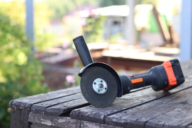 Kablosuz öğütücü yakın planda, ahşap bir yüzeye uzanıyor. Kulübede ya da inşaatta tamirat. Çalışan alet. Kablosuz kablosuz öğütücü. Elektrikli aletler. DIY tamir konsepti, inşaat ekipmanları