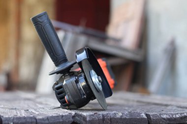 Kablosuz öğütücü yakın planda, ahşap bir yüzeye uzanıyor. Kulübede ya da inşaatta tamirat. Çalışan alet. Kablosuz kablosuz öğütücü. Elektrikli aletler. DIY tamir konsepti, inşaat ekipmanları