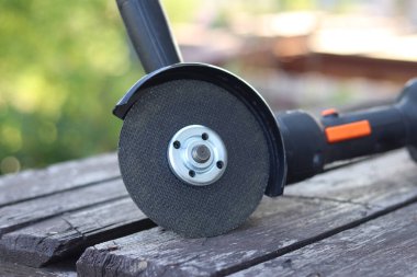 Kablosuz öğütücü yakın planda, ahşap bir yüzeye uzanıyor. Kulübede ya da inşaatta tamirat. Çalışan alet. Kablosuz kablosuz öğütücü. Elektrikli aletler. DIY tamir konsepti, inşaat ekipmanları