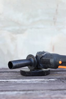 Kablosuz öğütücü yakın planda, ahşap bir yüzeye uzanıyor. Kulübede ya da inşaatta tamirat. Çalışan alet. Kablosuz kablosuz öğütücü. Elektrikli aletler. DIY tamir konsepti, inşaat ekipmanları