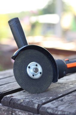 Kablosuz öğütücü yakın planda, ahşap bir yüzeye uzanıyor. Kulübede ya da inşaatta tamirat. Çalışan alet. Kablosuz kablosuz öğütücü. Elektrikli aletler. DIY tamir konsepti, inşaat ekipmanları