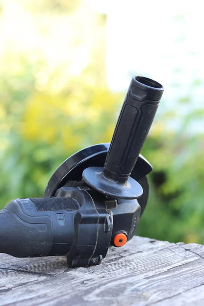 Kablosuz öğütücü yakın planda, ahşap bir yüzeye uzanıyor. Kulübede ya da inşaatta tamirat. Çalışan alet. Kablosuz kablosuz öğütücü. Elektrikli aletler. DIY tamir konsepti, inşaat ekipmanları