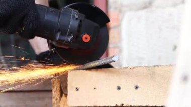 Angle grinder cuts reinforcement, sparks fly, construction work close-up. Electric tool for construction and repair work. Grinder with metal disc. Close-up of hands in gloves with grinder. Repair work