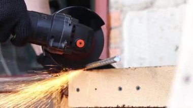 Angle grinder cuts reinforcement, sparks fly, construction work close-up. Electric tool for construction and repair work. Grinder with metal disc. Close-up of hands in gloves with grinder. Repair work