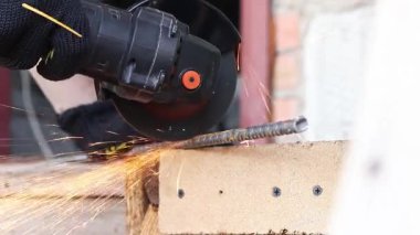 Angle grinder cuts reinforcement, sparks fly, construction work close-up. Electric tool for construction and repair work. Grinder with metal disc. Close-up of hands in gloves with grinder. Repair work