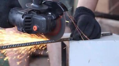 Angle grinder cuts reinforcement, sparks fly, construction work close-up. Electric tool for construction and repair work. Grinder with metal disc. Close-up of hands in gloves with grinder. Repair work