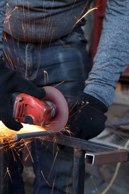 Angle grinder cutting rebar, sparks flying. Angle grinder with metal disc and no casing, safety violation. Close-up of gloved hands with grinder. Repair work. Close-up of construction work in progress